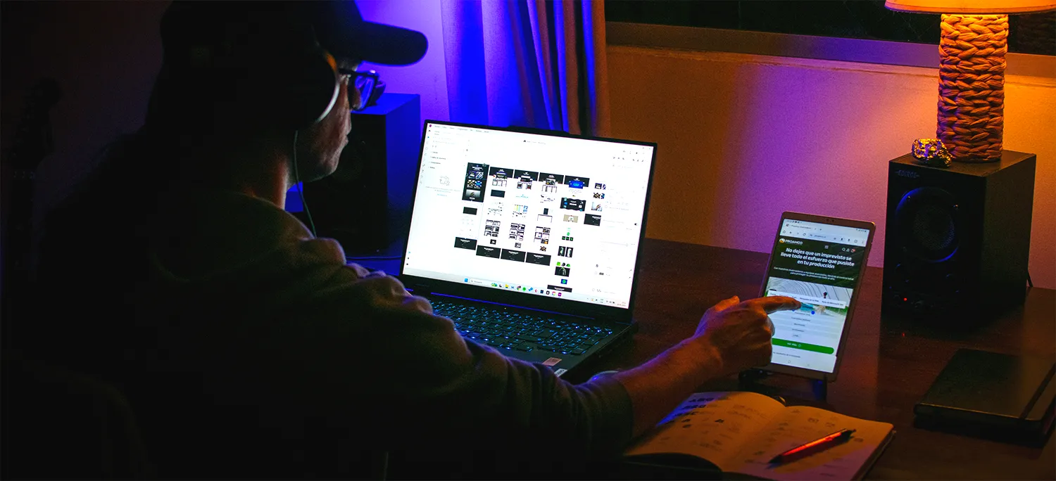 Photo of Sergio Grez, web designer working on a laptop and pointing to a tablet